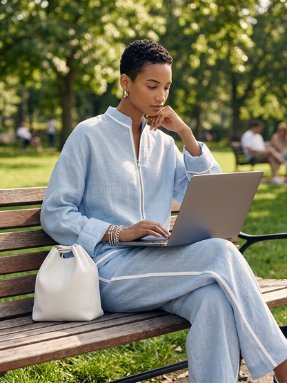 Woman wearing the light blue linen two-piece set while sitting on a park bench