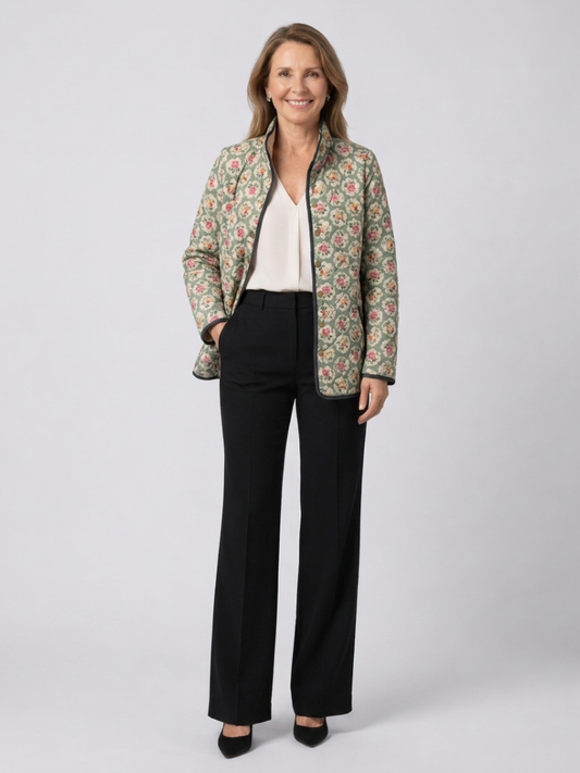 Woman wearing the Seraphine quilted floral tapestry jacket open over an ivory top with black trousers