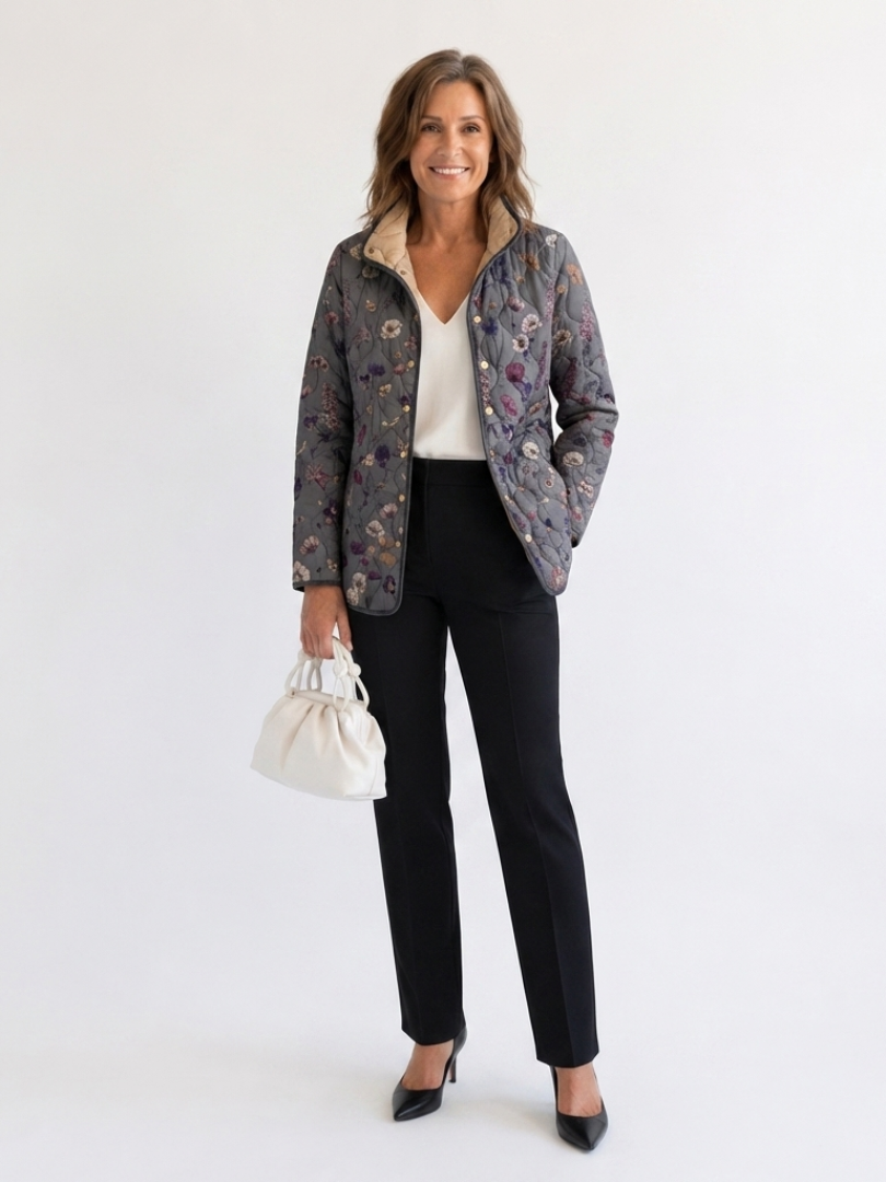 Woman wearing the Dorothea quilted dried flower jacket open over an ivory top with black trousers
