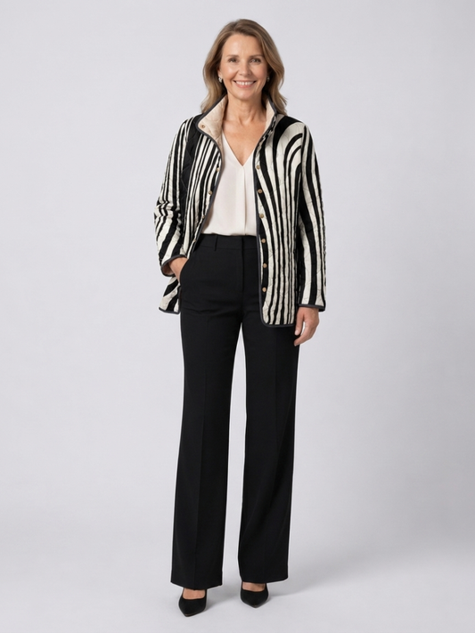 Woman wearing the Philippa quilted graphic zebra jacket open over an ivory top with black trousers