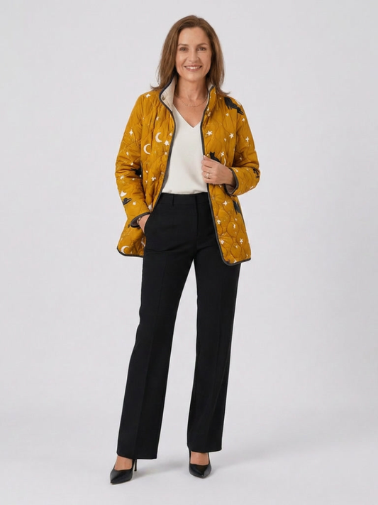 Woman wearing the Winifred quilted cat and star jacket open over an ivory top with black trousers