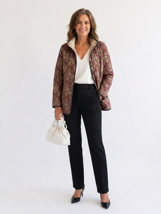 Woman wearing the Augustine quilted damask jacket open over an ivory top with black trousers