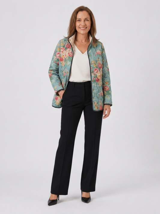 Woman wearing the Adelaide quilted celadon rose jacket open over an ivory top with black trousers