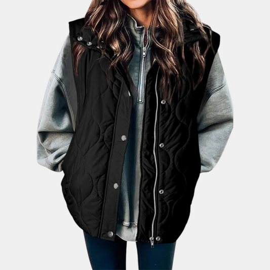 Juliette black quilted hooded puffer vest layered over a gray hoodie, front view