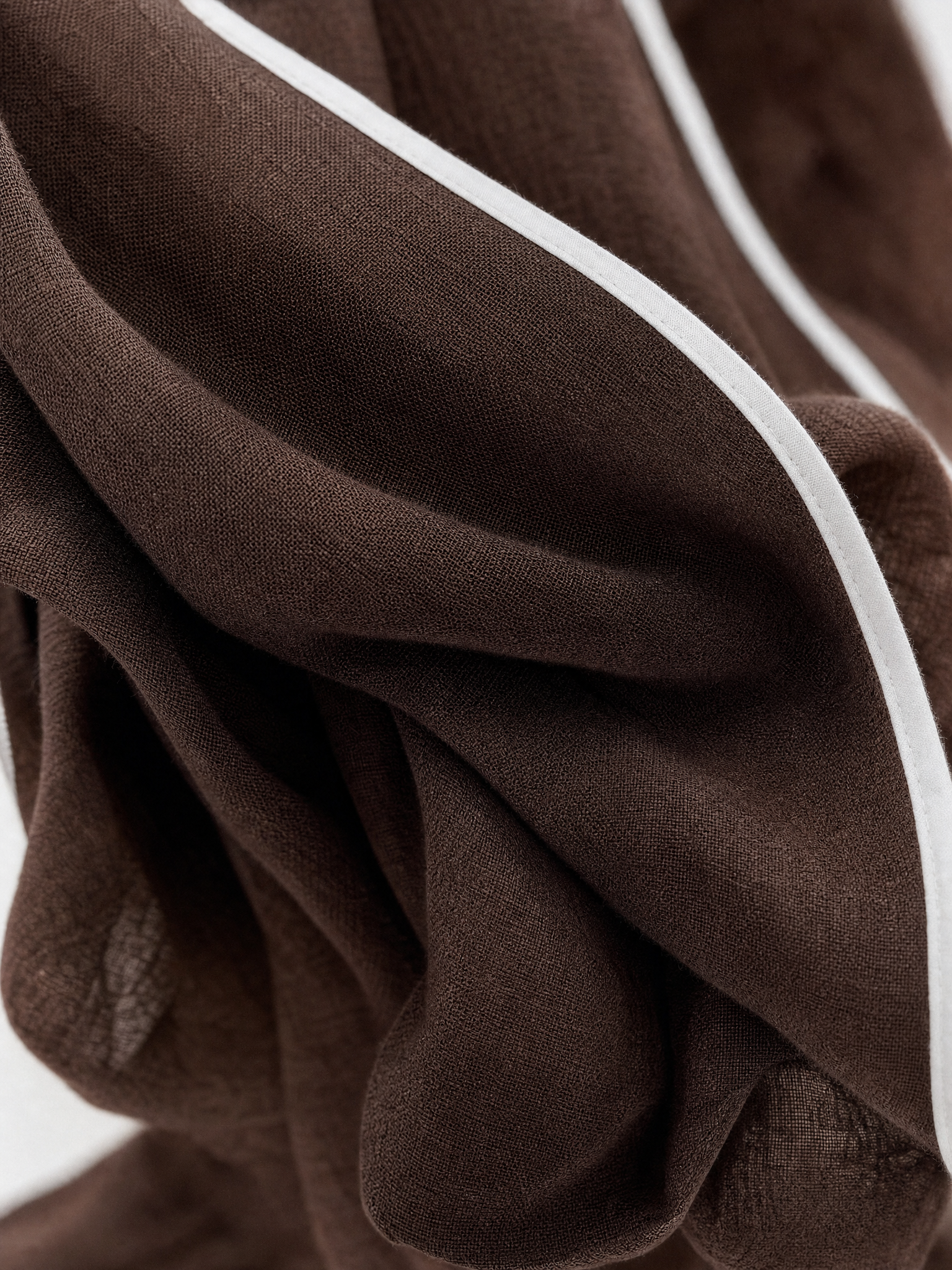 Close-up of the brown linen blend fabric with white piping